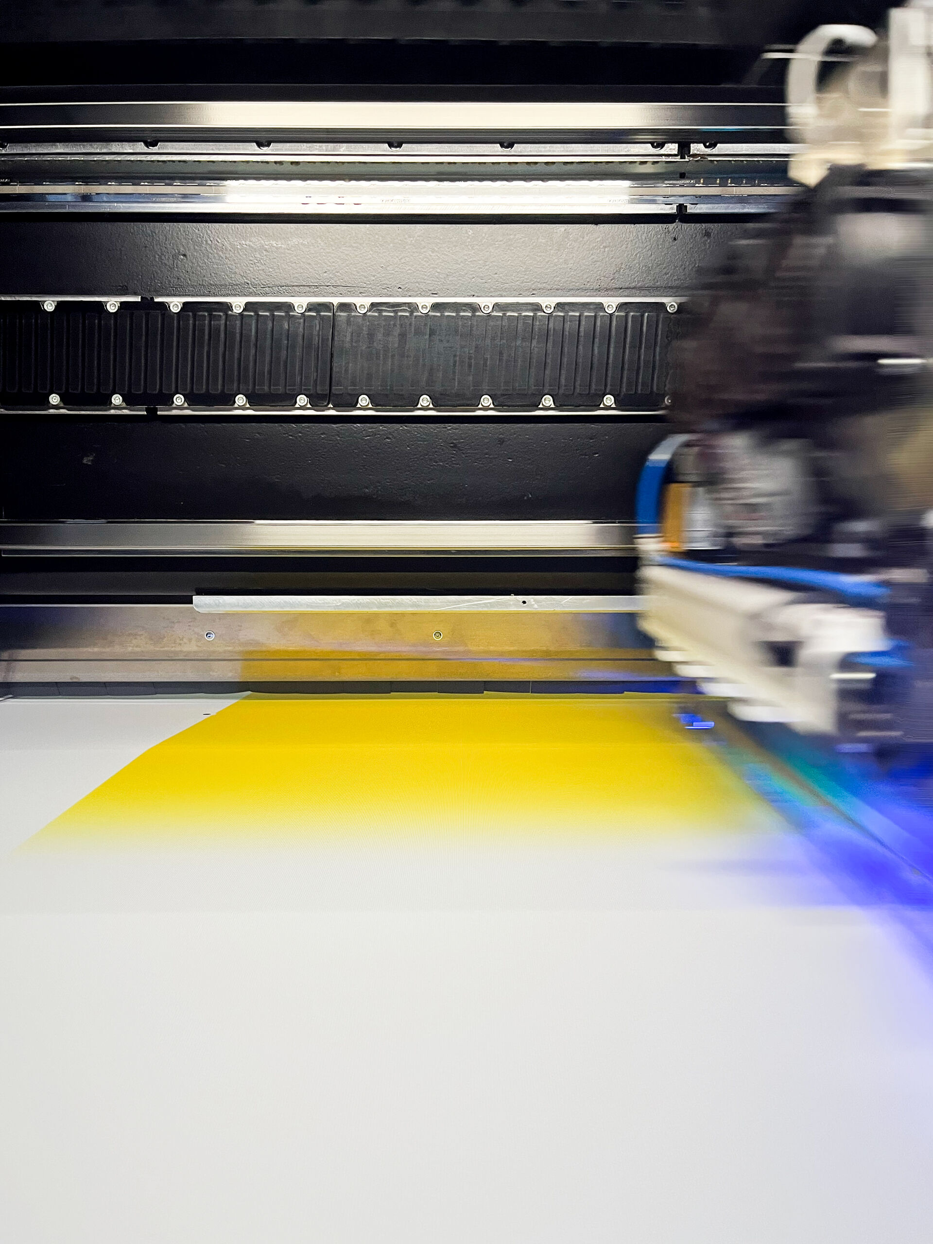 Innenansicht eines Großformatdigitaldrucker, auf dem ein gelbes Motiv gedruckt wird.