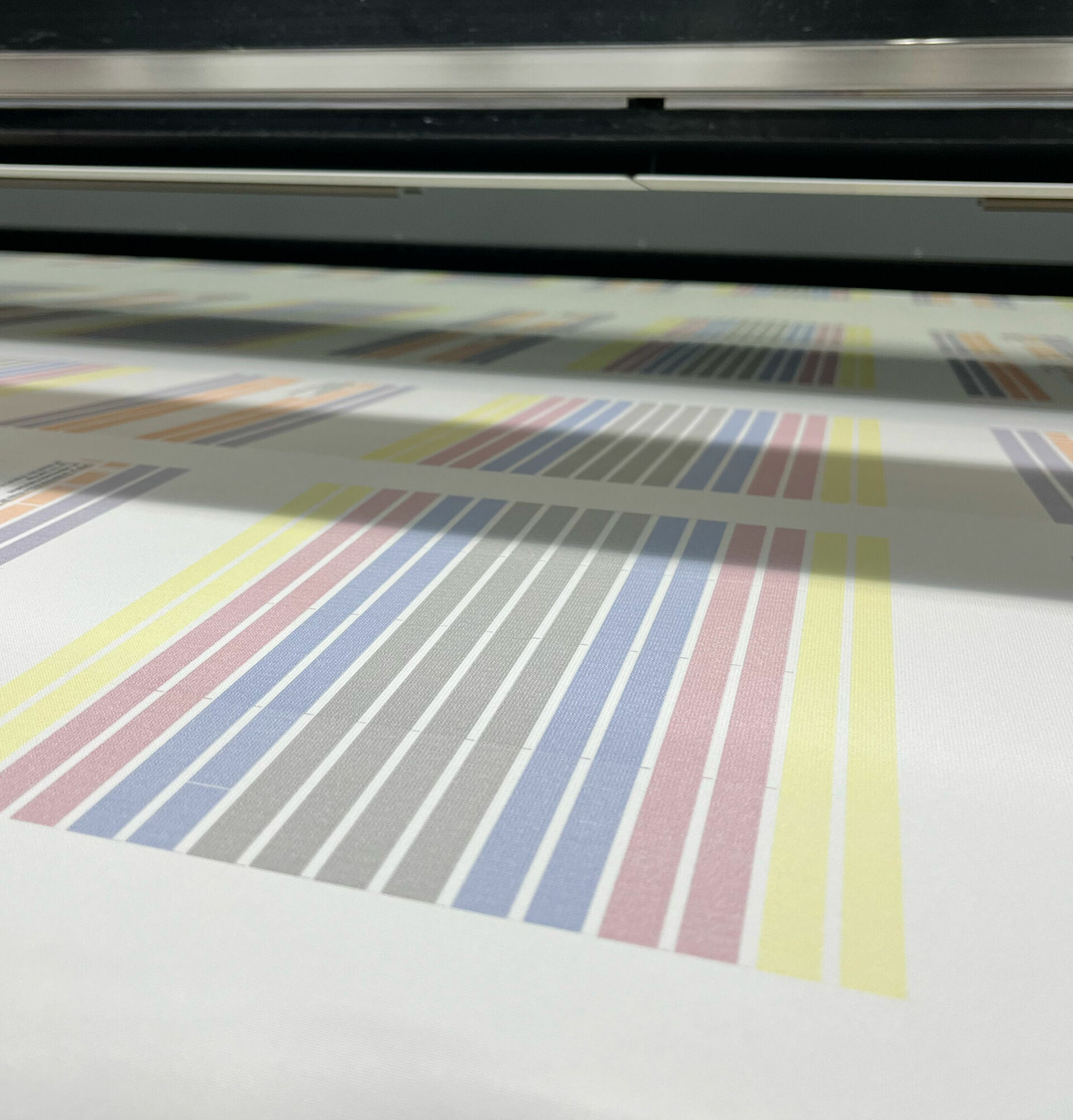 Gedruckte Teststreifen auf einem weißem Textil innerhalb einer Großformat-Druckmaschine