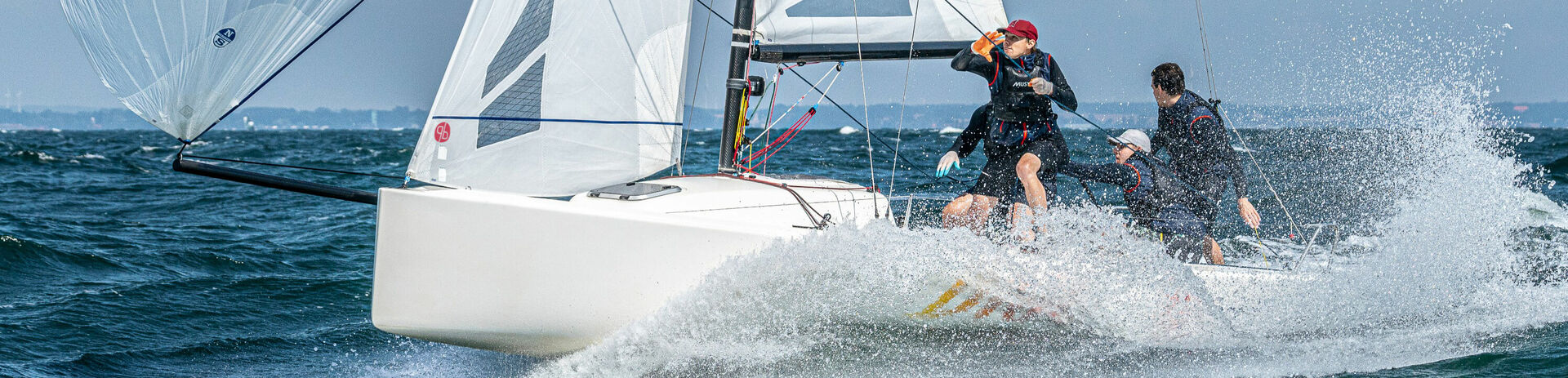 Eine Sportyacht mit zwei Seglern auf dem Meer.